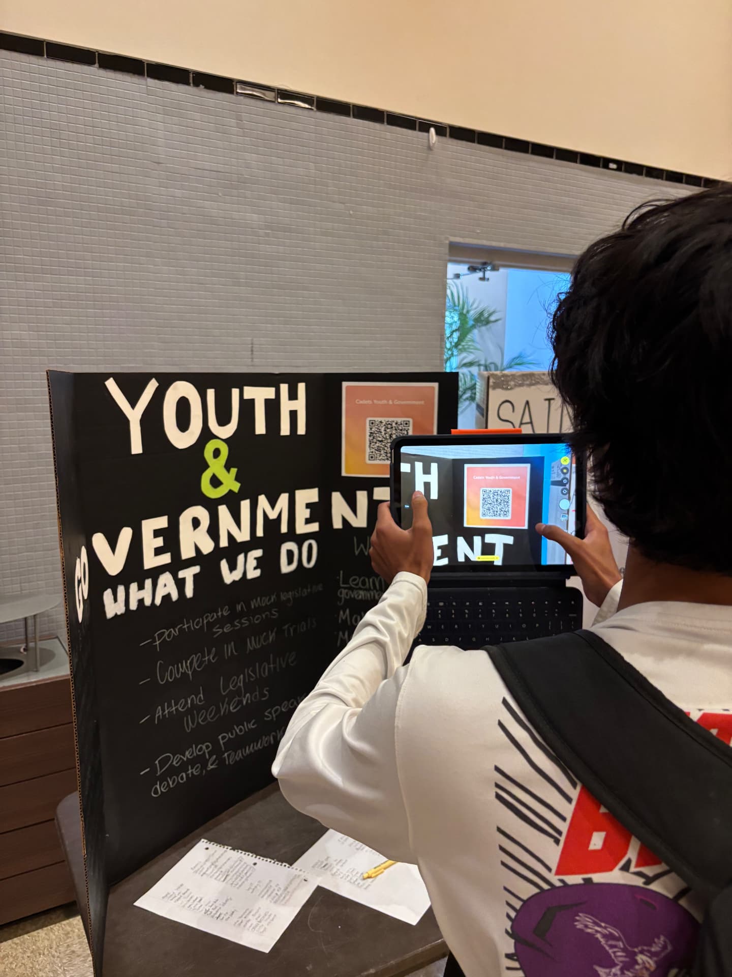 A student photographing the Youth & Government club booth with a tablet